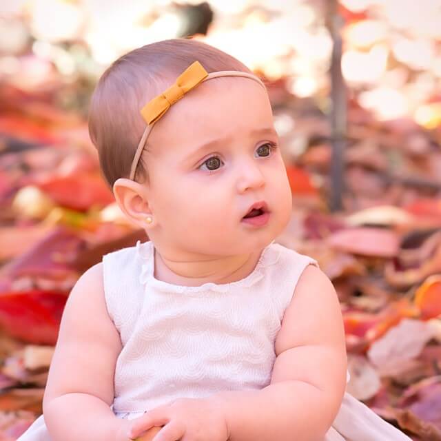 Baby bow on a baby girl sitting in leaves