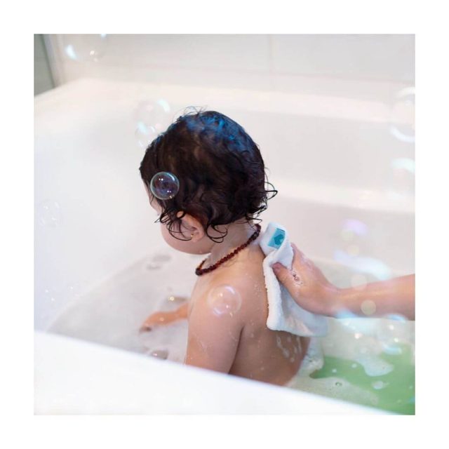 baby in bath being washed with a baby washcloth