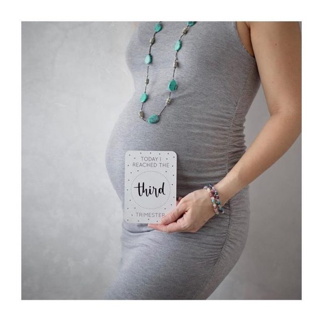 pregnant women holding milestone card